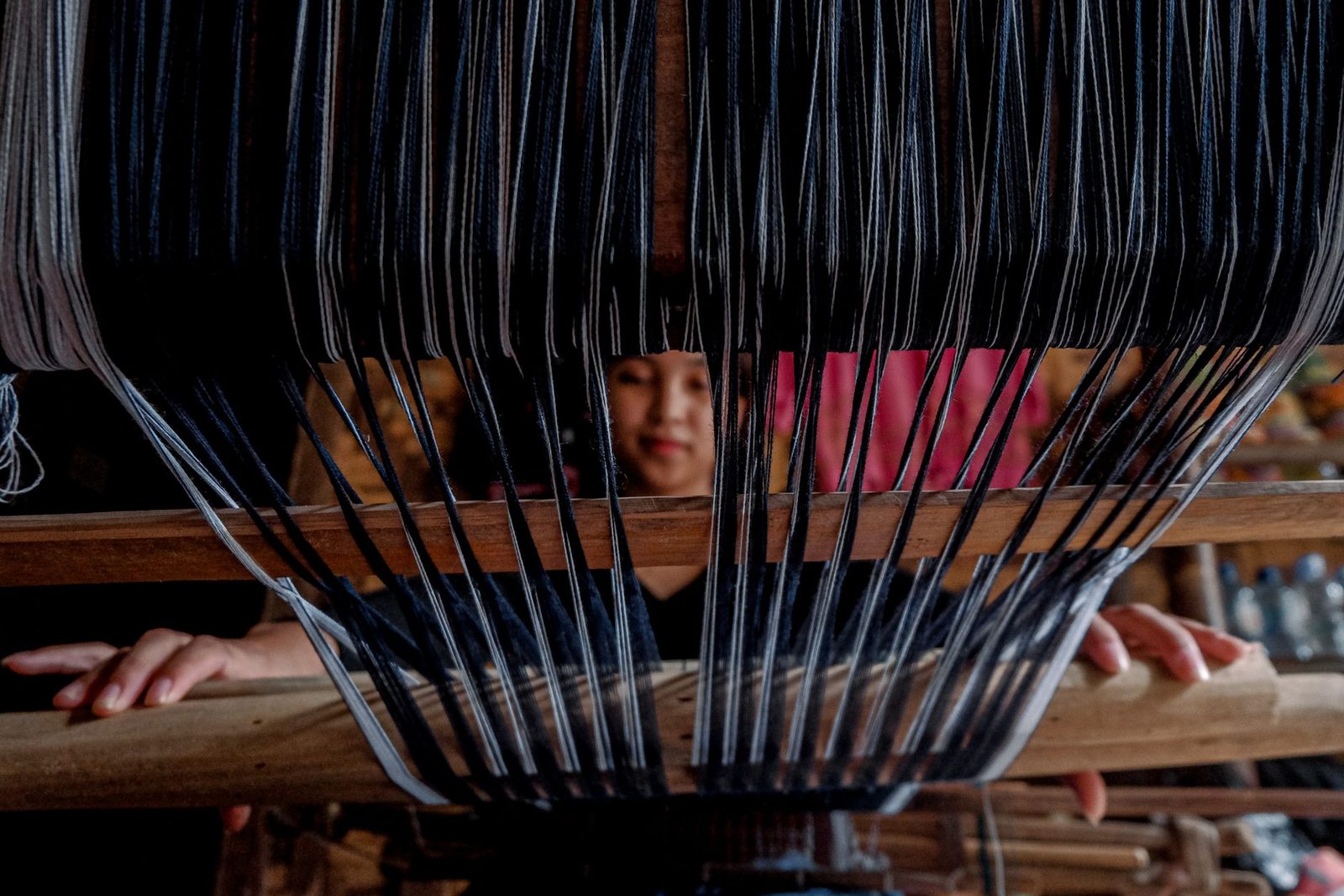 A weaver at work behind a strung loom
